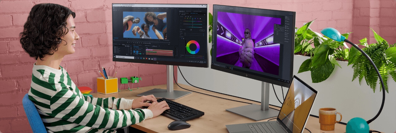 شاب يعمل باستخدام كمبيوتر محمول HP ENVY x360 متصل بشاشتين من HP