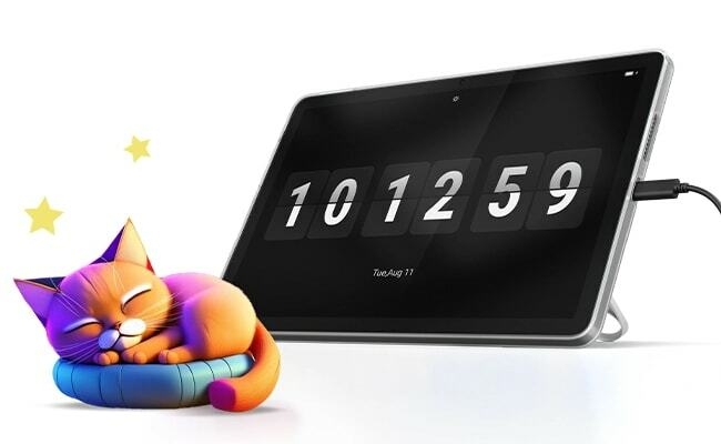 جهاز Lenovo Tab في وضع الحامل يعرض واجهة ساعة، وبجواره قطة كرتونية ملونة نائمة.