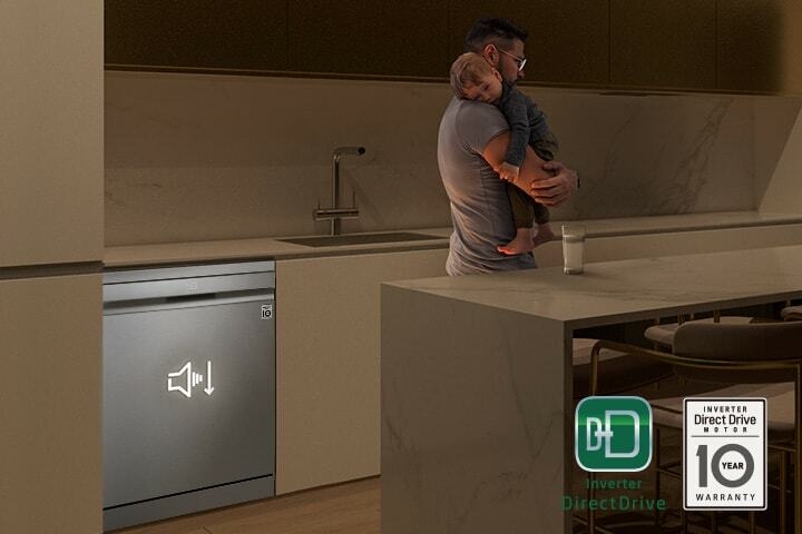 Man holding a sleeping child while a quiet dishwasher runs in the background