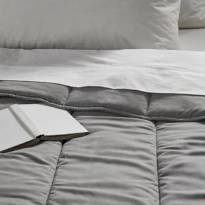 Comforter Grey comforter with silky smooth texture on bed, open book resting on it.