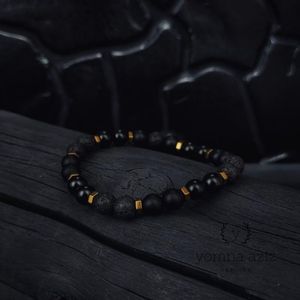 سوار أنيق من حجر اللافا الأسود مع أحجار سوداء وتفاصيل ذهبية، بتصميم عصري يناسب الرجال والنساء، مثالي للإطلالات اليومية والمناسبات.